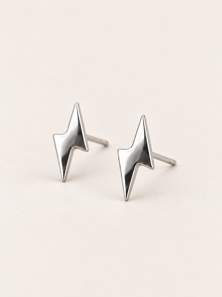 Silver Lightning Bolt Stud Earrings shown angled on a warm neutral background