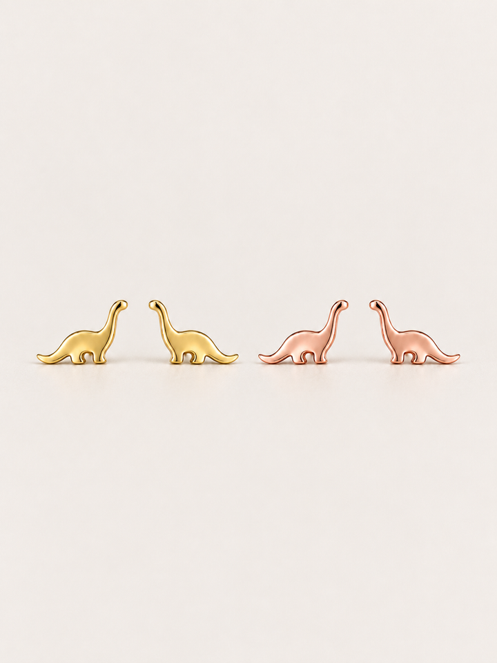 Long Neck Dinosaur Stud Earrings in gold and rose gold shown on a warm neutral background