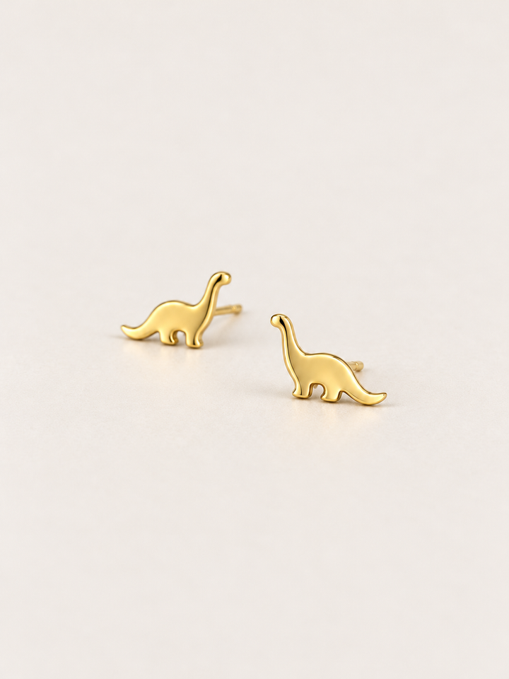 Long Neck Dinosaur Stud Earrings in gold shown angled on a warm neutral background