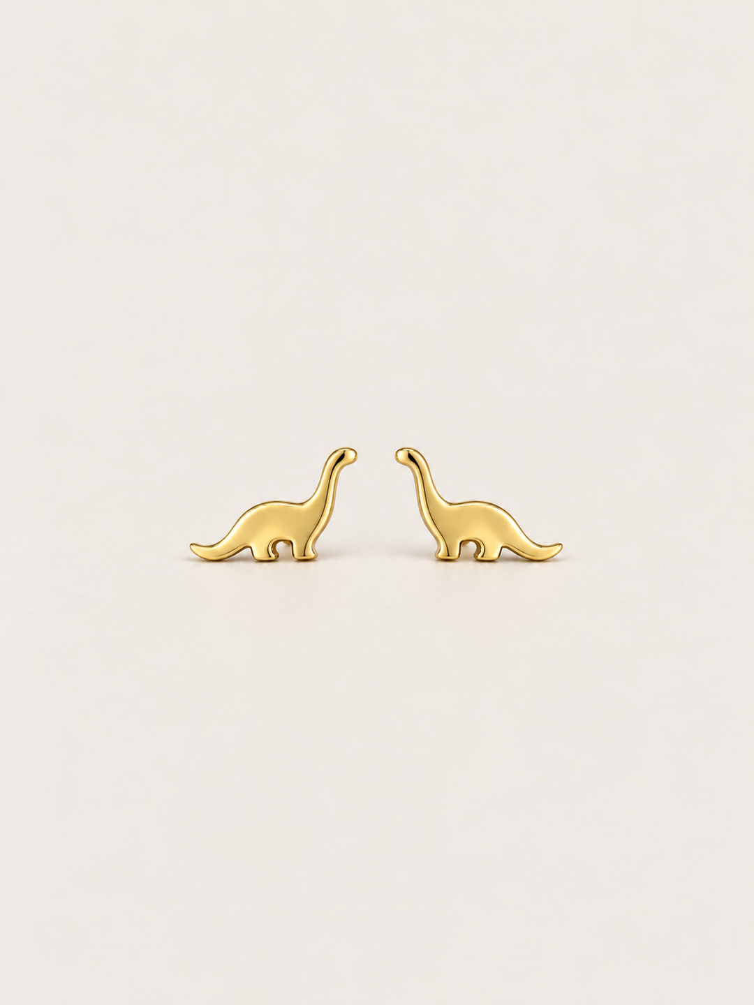 Long Neck Dinosaur Stud Earrings in gold on a warm neutral background