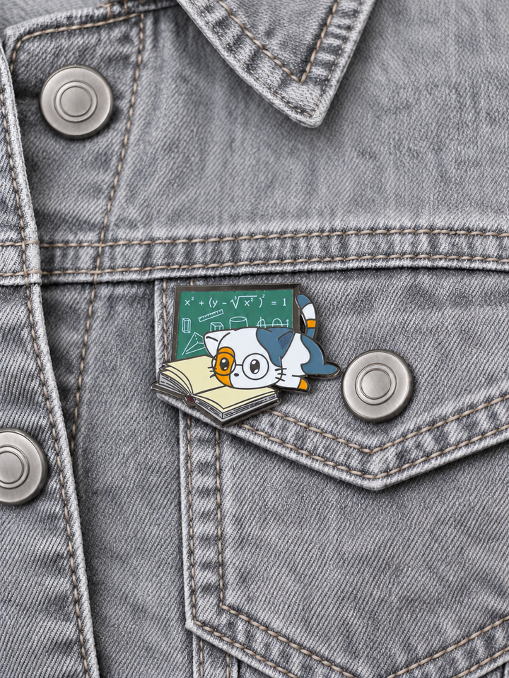 Math Study Cat Pin displayed on a pale gray denim jacket beside a metal button