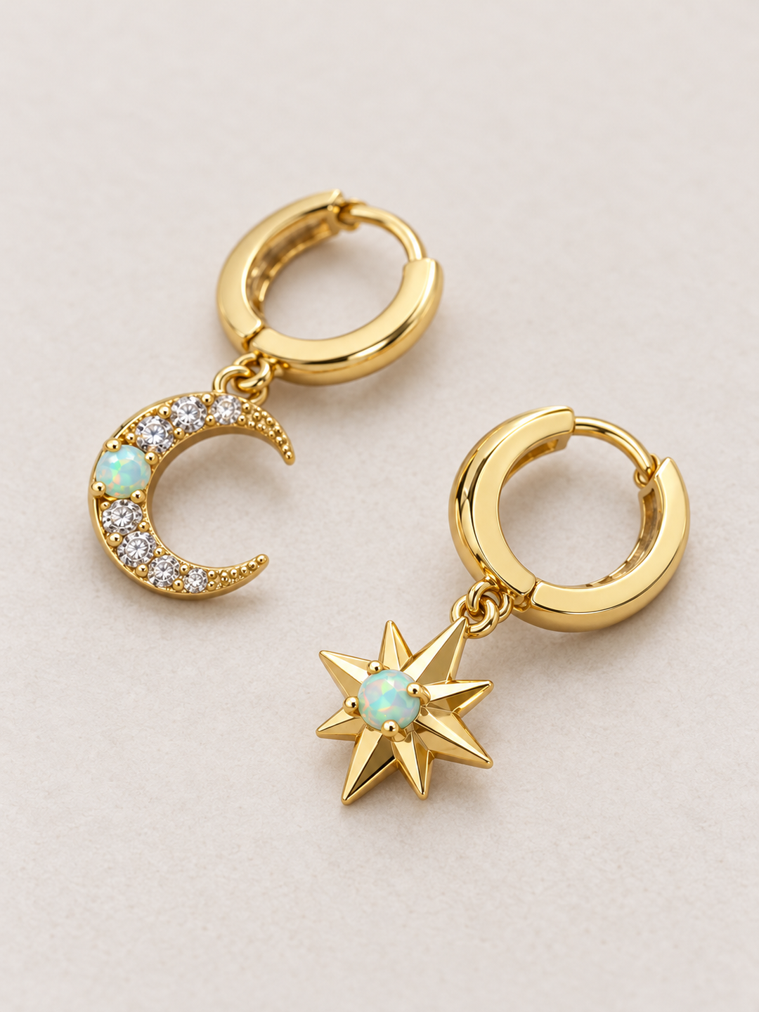 Moon and Star Huggie Earrings shown angled on a warm neutral background