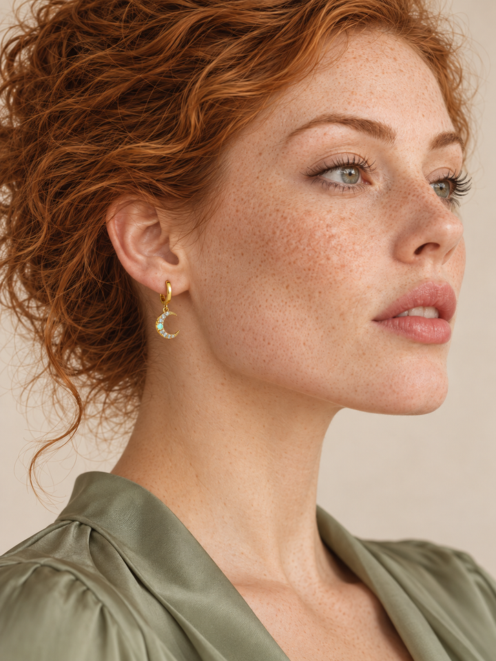 Crescent moon gold huggie worn on the viewer-left ear