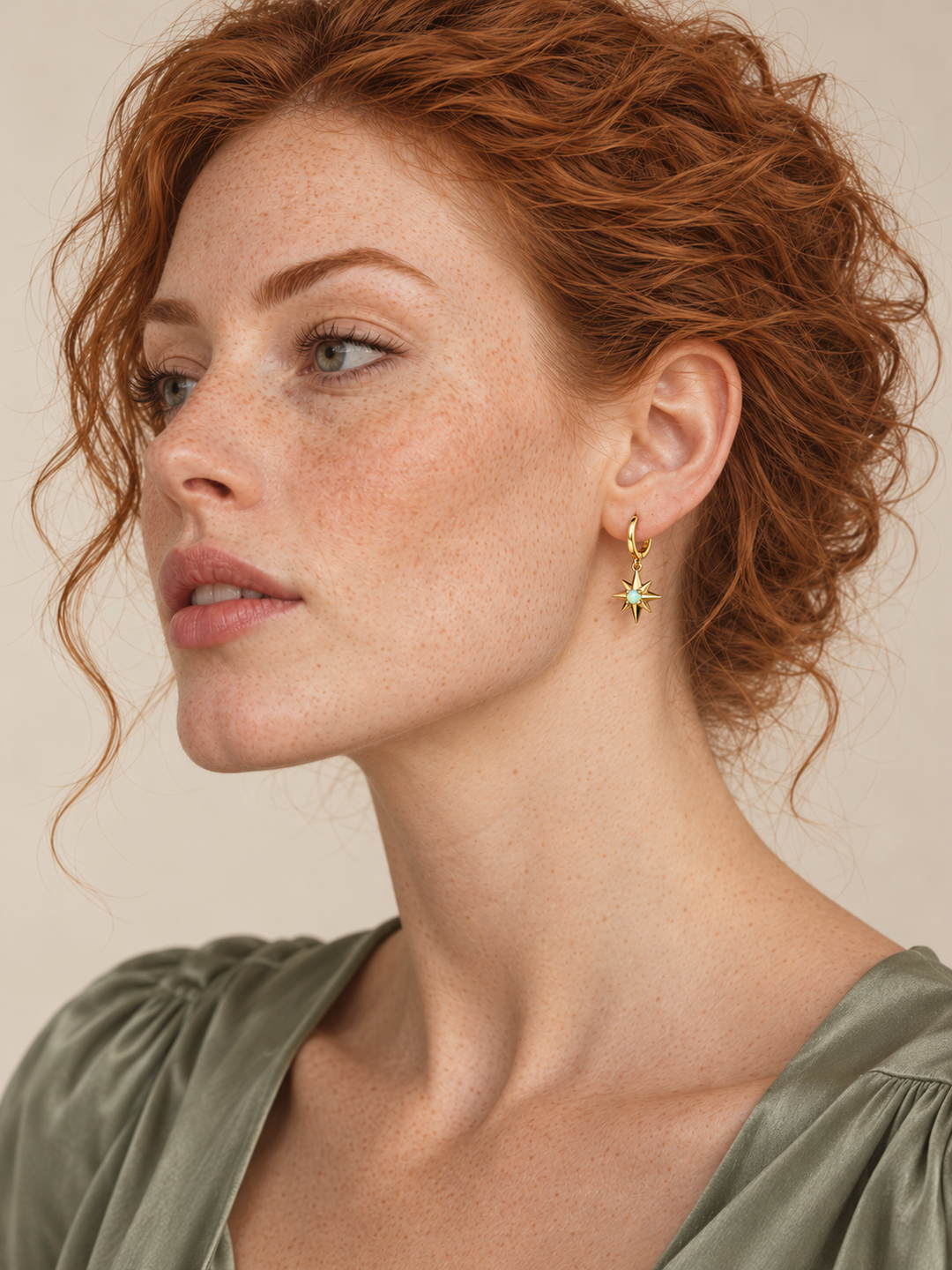 Eight-point star gold huggie worn on the viewer-right ear