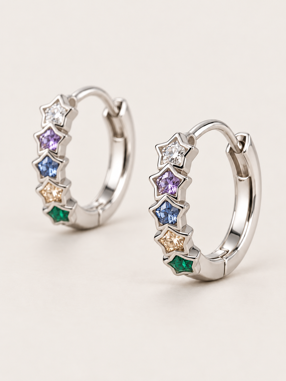 Multicolor Star Huggie Earrings shown angled on a warm neutral background