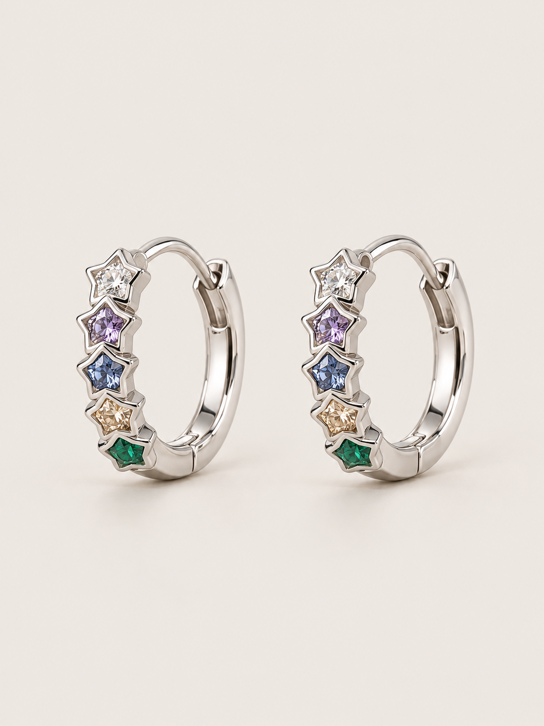 Multicolor Star Huggie Earrings shown on a warm neutral background