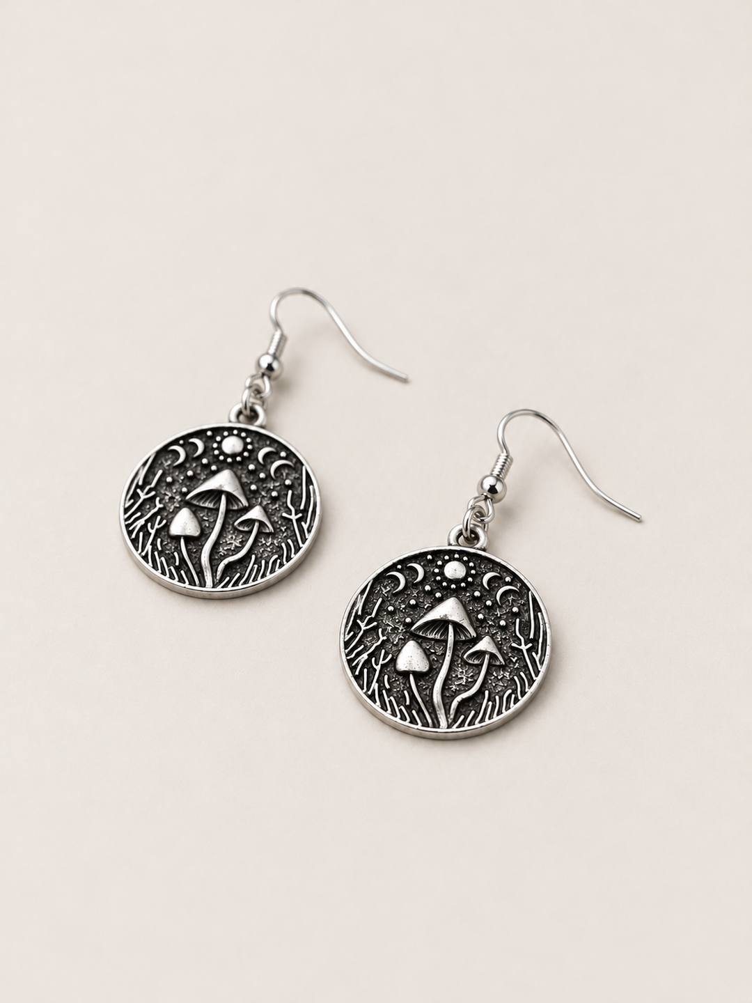 Mushroom Forest Drop Earrings lying flat at an angle on a warm neutral background