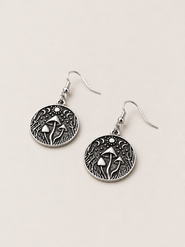 Mushroom Forest Drop Earrings lying flat at an angle on a warm neutral background