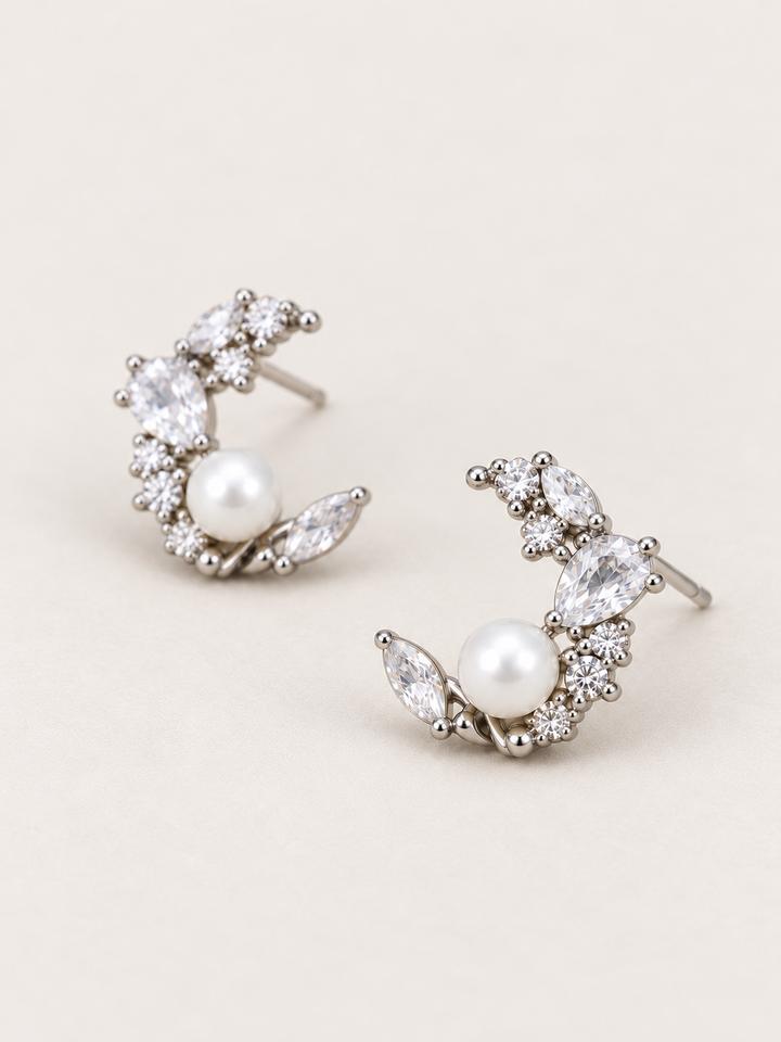 Silver Pearl Crystal Crescent Earrings shown angled on a warm neutral background