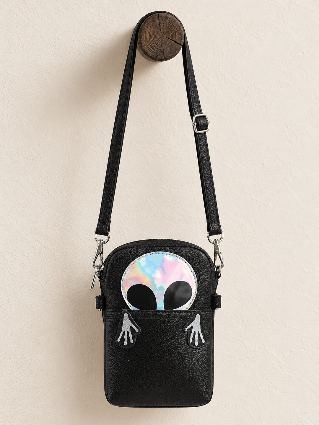 Peeking Alien Crossbody Bag hanging from a wooden post