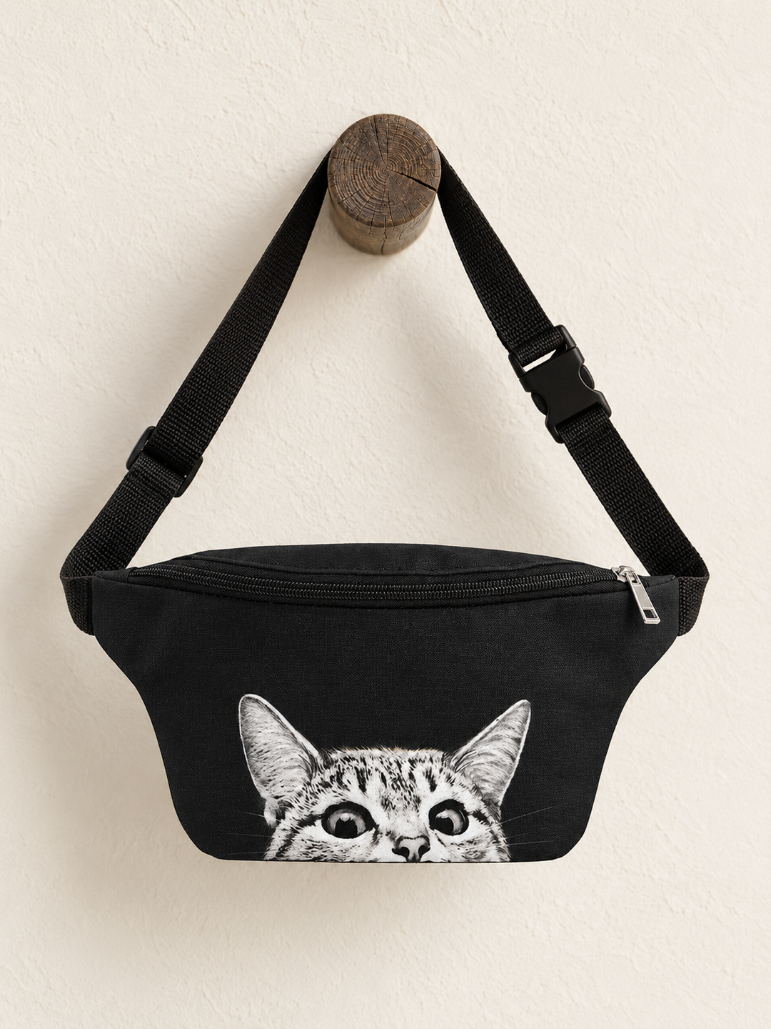 Peeking Cat Fanny Pack hanging from a wooden post