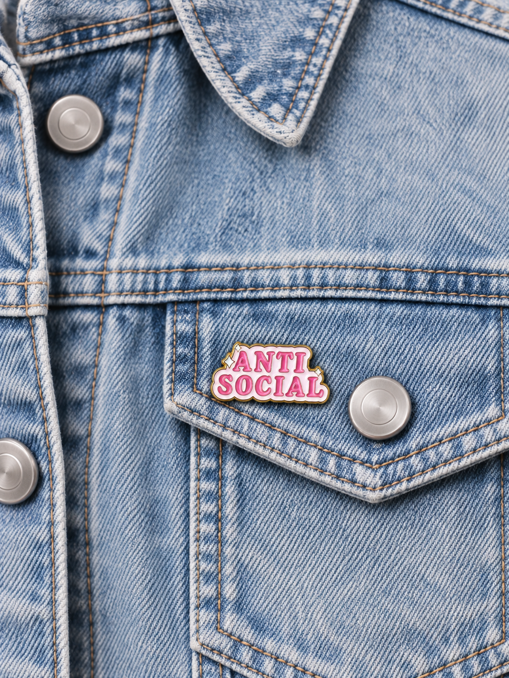 Pink Anti Social Pin displayed left of a centered button on a light-wash denim pocket