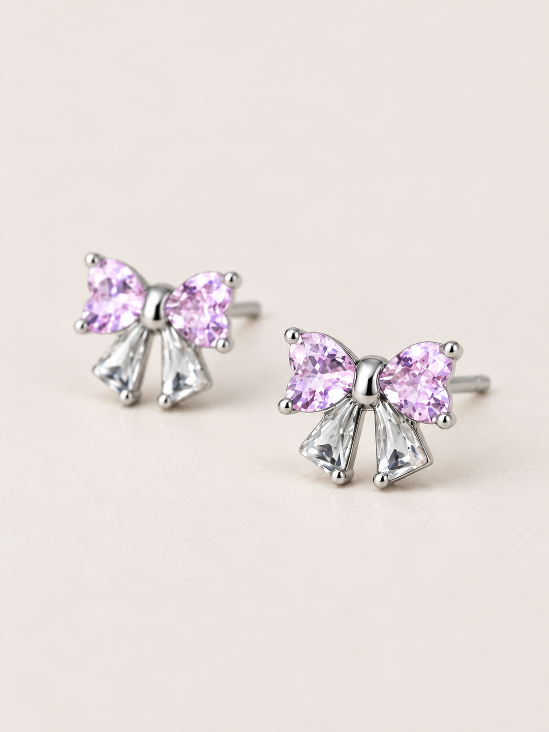 Pink Crystal Bow Stud Earrings shown angled on a warm neutral background