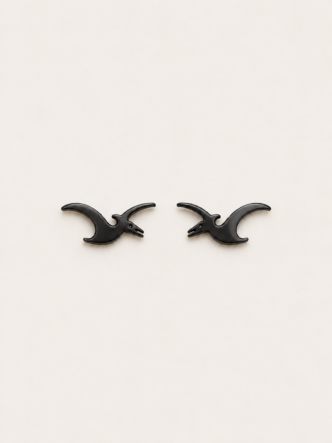 Pterodactyl Stud Earrings in Black on a warm neutral background