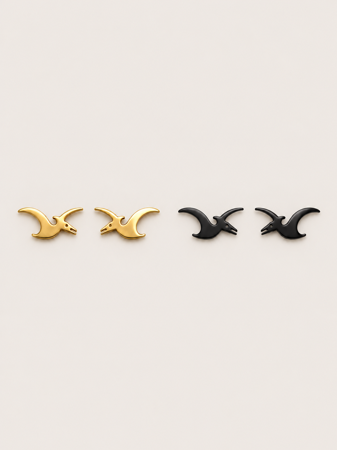Pterodactyl Stud Earrings in Gold and Black on a warm neutral background