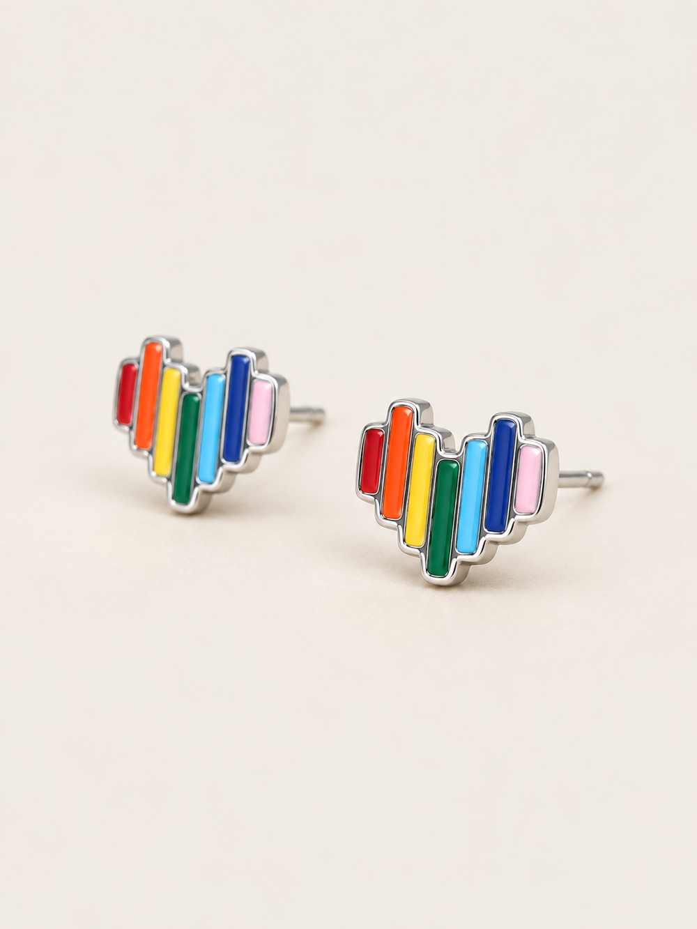 Rainbow Heart Stud Earrings shown angled on a warm neutral background