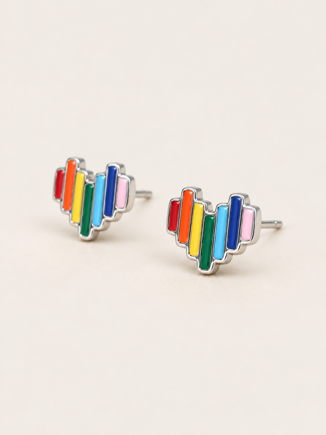 Rainbow Heart Stud Earrings shown angled on a warm neutral background