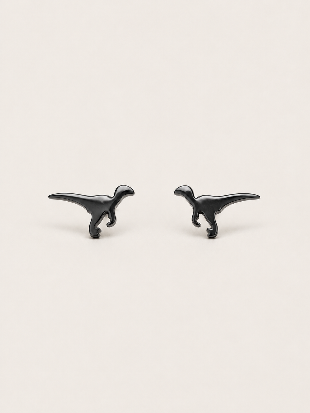 Black Raptor Dinosaur Stud Earrings shown on a warm neutral background