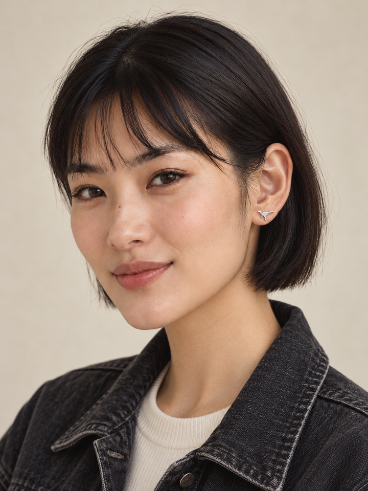 Silver Raptor Dinosaur Stud Earrings worn on the viewer-right ear