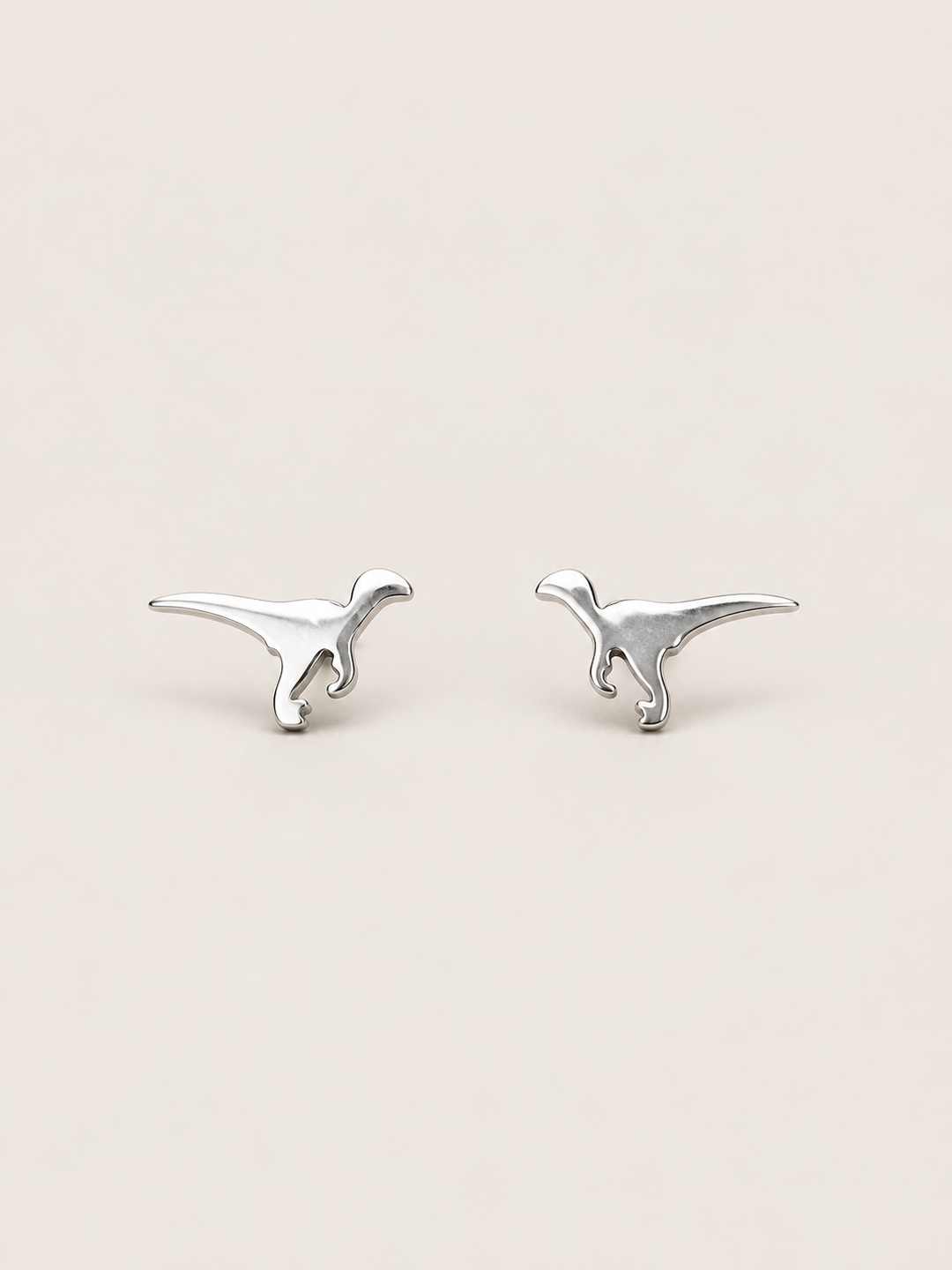Silver Raptor Dinosaur Stud Earrings shown on a warm neutral background