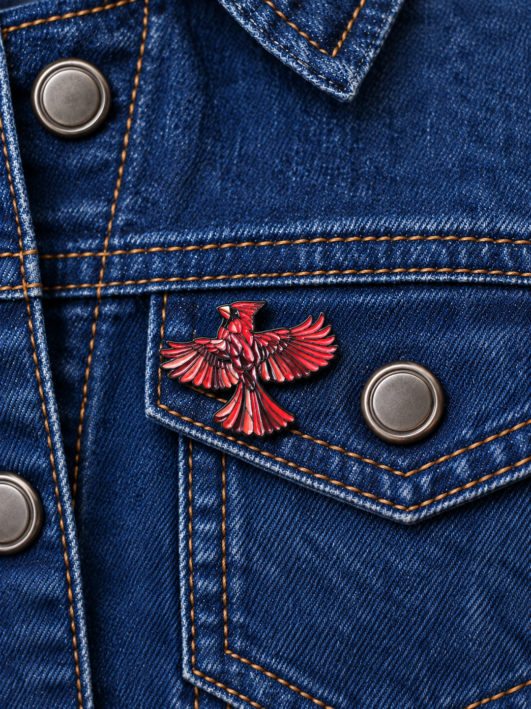 Red Cardinal Wings Spread Pin displayed on a dark indigo denim jacket beside a metal button