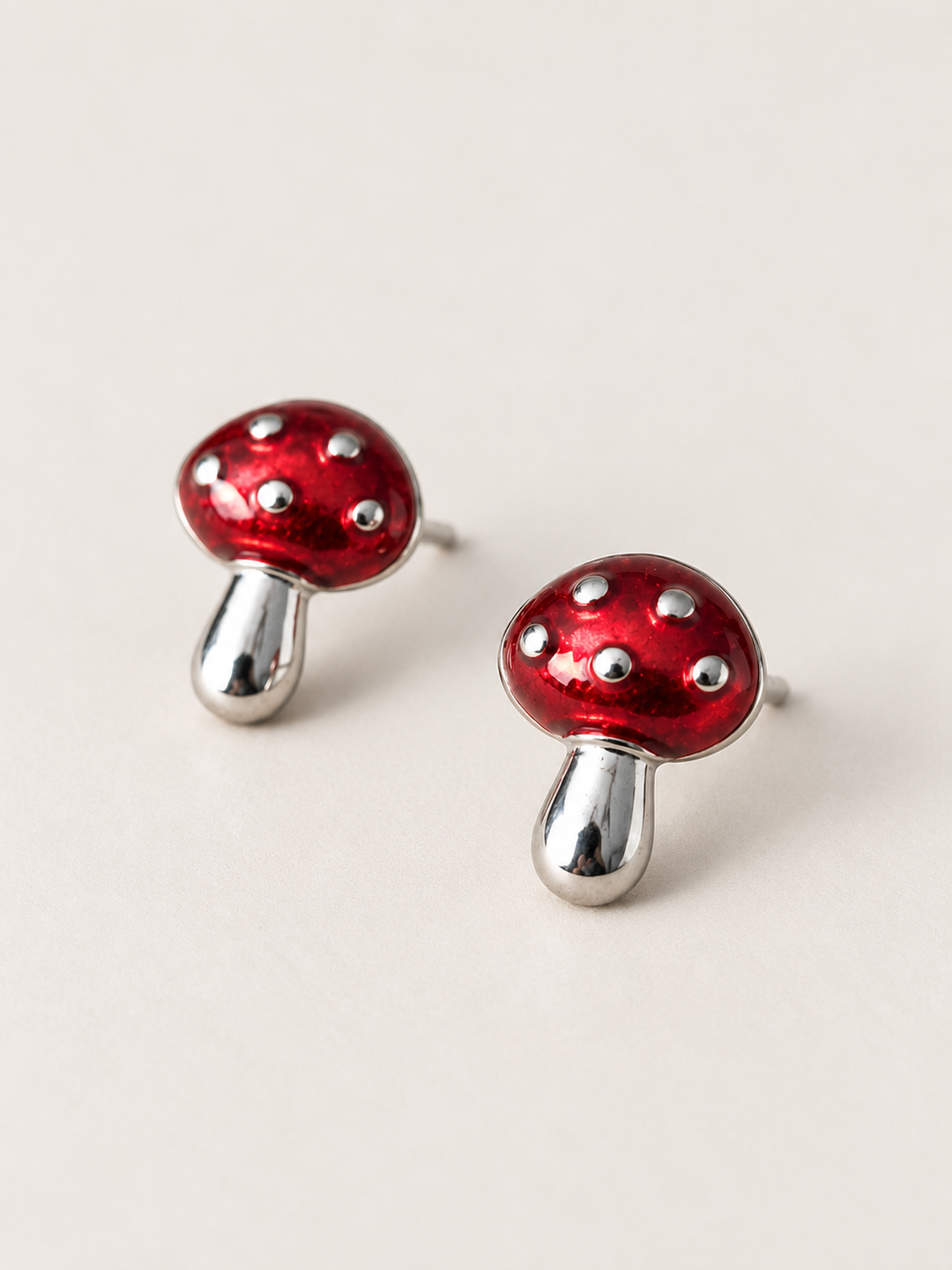 Red Mushroom Stud Earrings shown angled on a warm neutral background