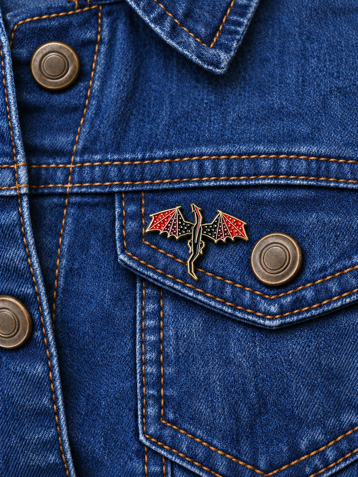 Red Winged Dragon Pin displayed on a dark indigo denim jacket beside a metal button