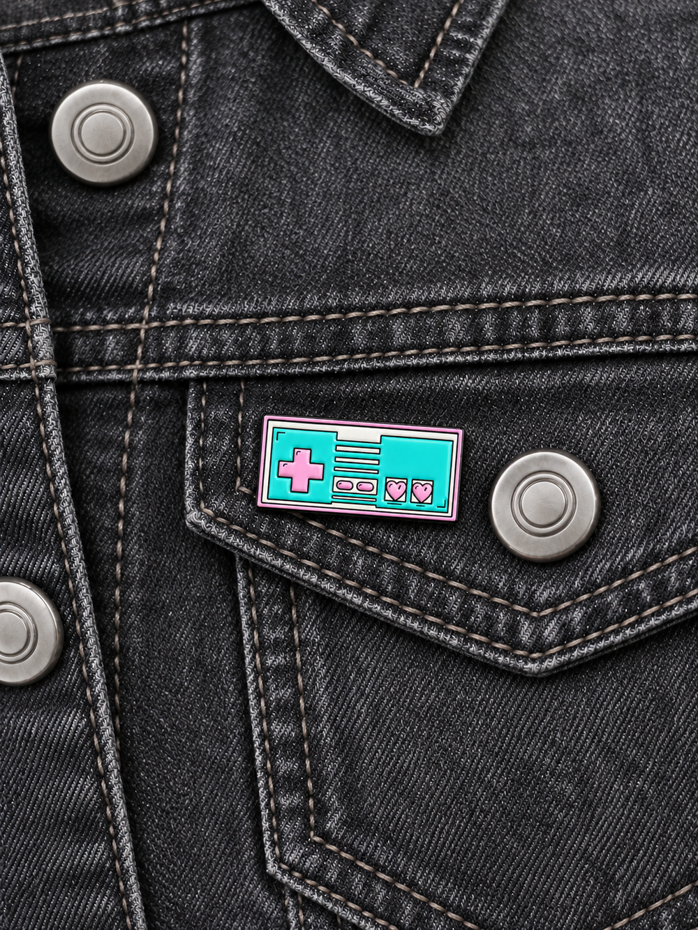 Retro Video Game Controller Pin displayed on a charcoal denim jacket beside a metal button