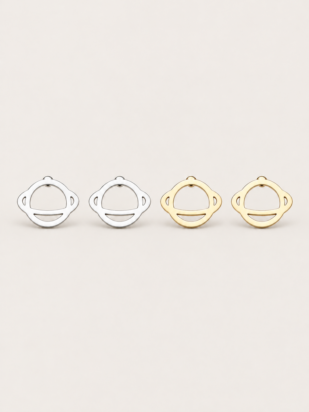 Ringed Planet Stud Earrings in silver and gold on a warm neutral background