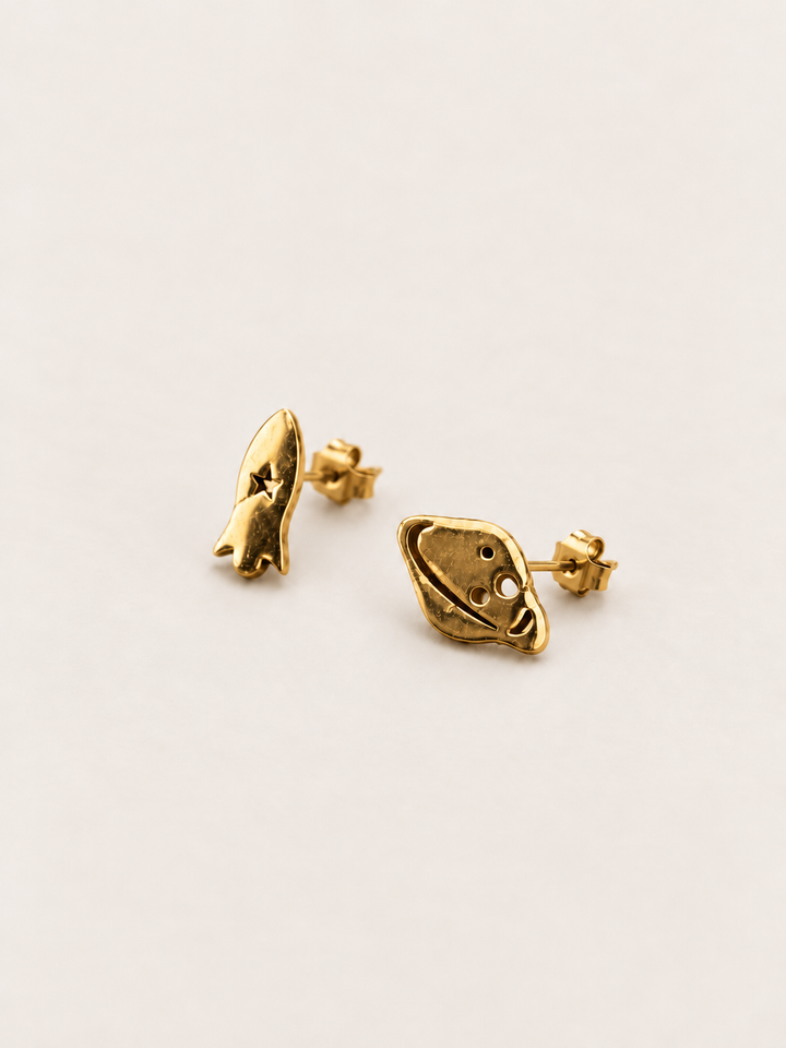 Gold Rocket and Planet Stud Earrings shown angled on a warm neutral background