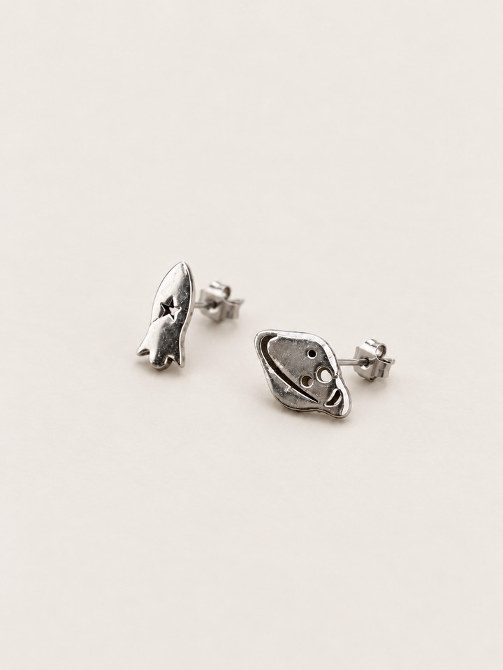 Silver Rocket and Planet Stud Earrings shown angled on a warm neutral background