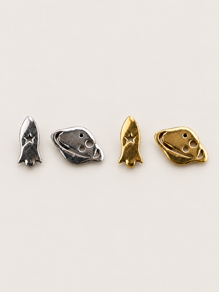 Rocket and Planet Stud Earrings in silver and gold on a warm neutral background