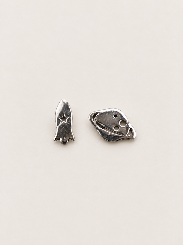 Silver Rocket and Planet Stud Earrings on a warm neutral background