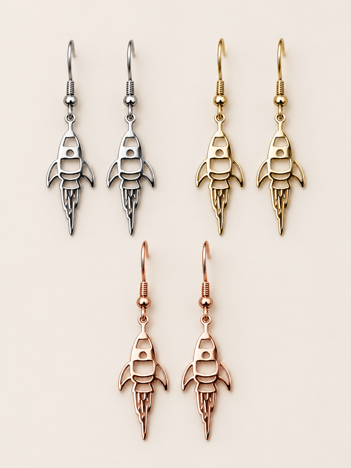 Rocket Drop Earrings in silver, gold, and rose gold on a warm neutral background