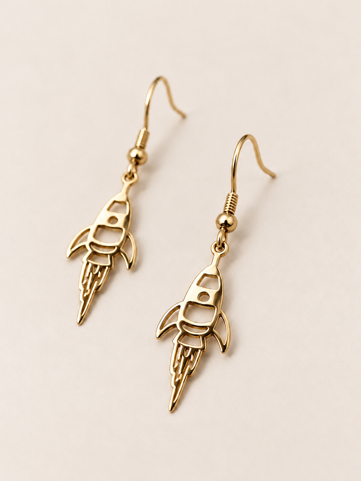 Gold Rocket Drop Earrings shown angled on a warm neutral background