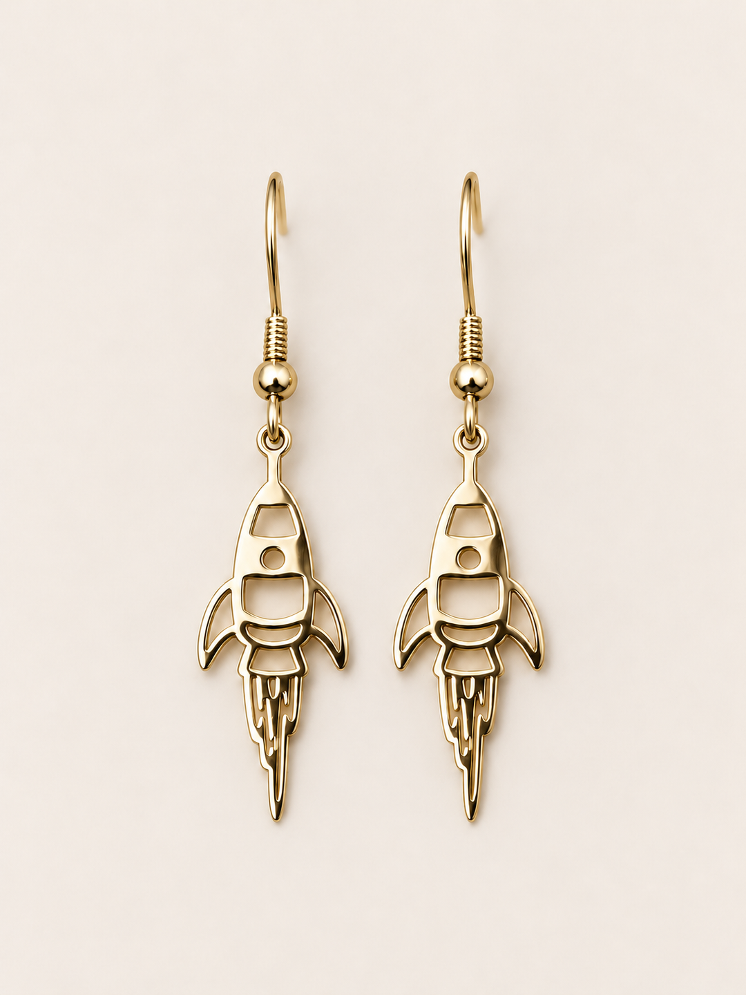 Gold Rocket Drop Earrings on a warm neutral background