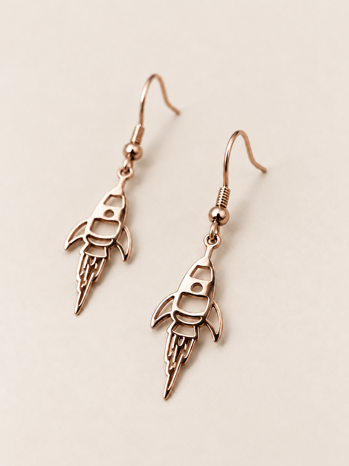 Rose Gold Rocket Drop Earrings shown angled on a warm neutral background