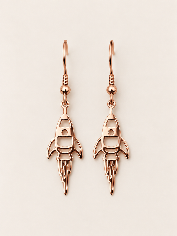 Rose Gold Rocket Drop Earrings on a warm neutral background
