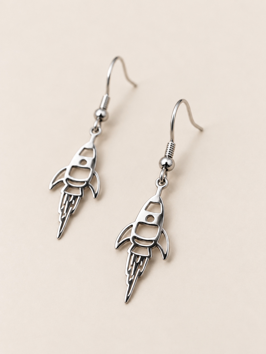 Silver Rocket Drop Earrings shown angled on a warm neutral background