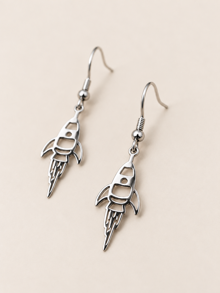 Silver Rocket Drop Earrings shown angled on a warm neutral background