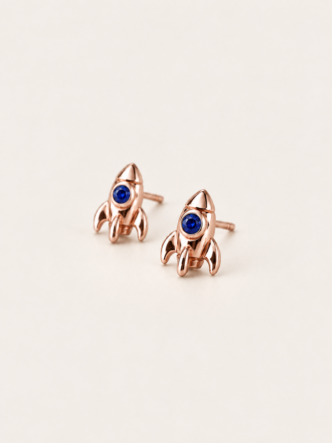 Rocket Stud Earrings in Rose Gold shown angled on a warm neutral background