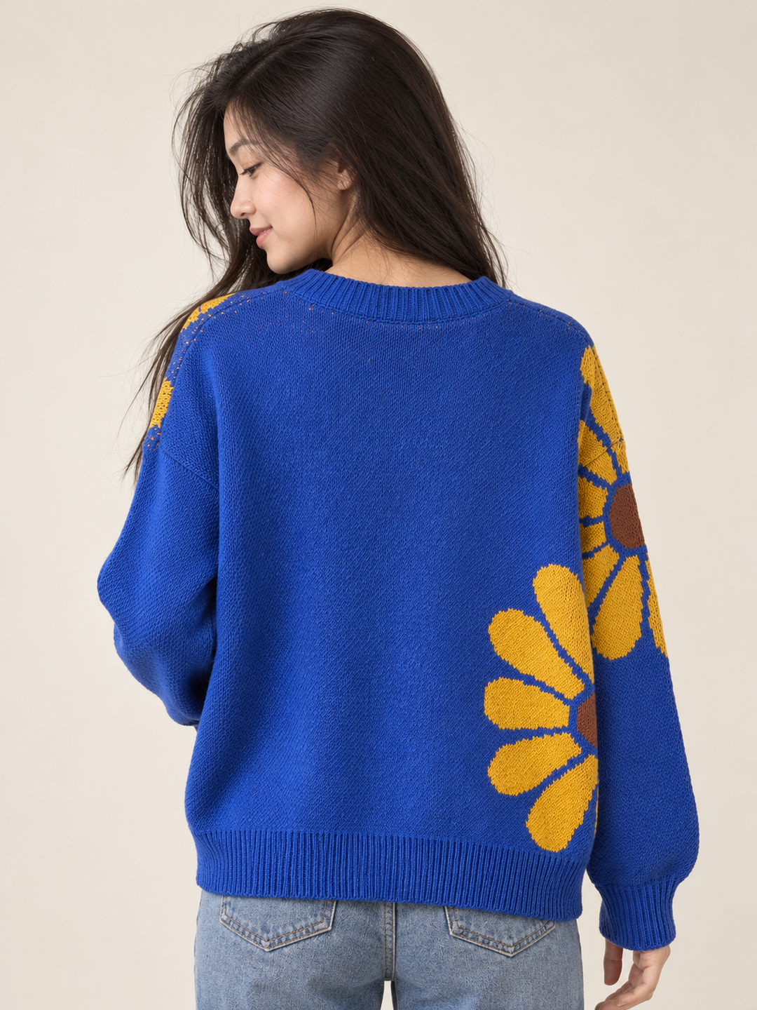 Back view of royal blue knit sweater with yellow daisy at the side
