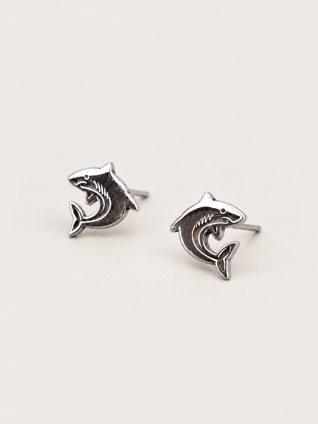 Shark Stud Earrings shown angled on a warm neutral background
