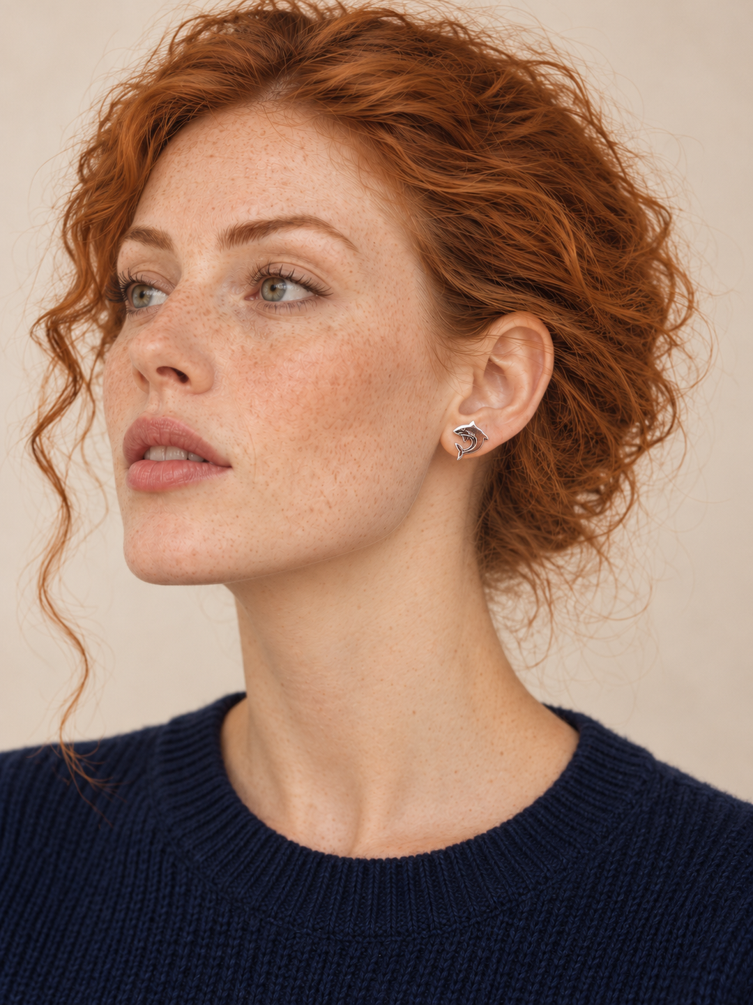 Silver stainless steel Shark Stud Earrings worn by a model in a dark blue sweater