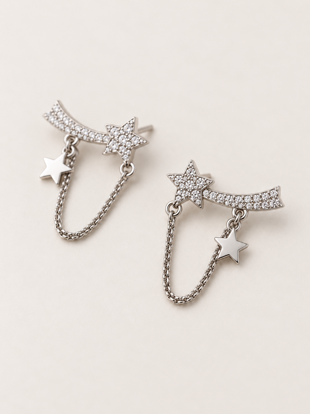 Shooting Star Chain Earrings shown angled on a warm neutral background