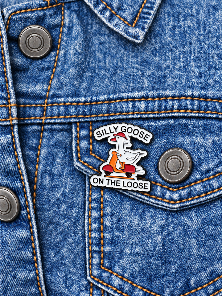 Silly Goose on the Loose Pin displayed on a stonewash denim jacket beside a metal button