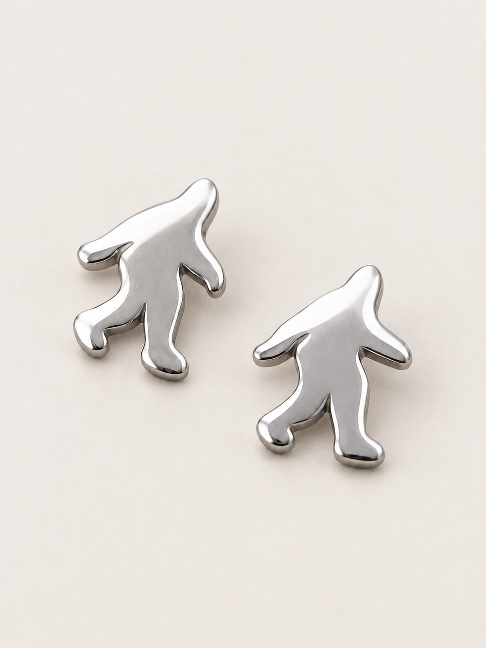 Silver Bigfoot Stud Earrings shown angled on a warm neutral background