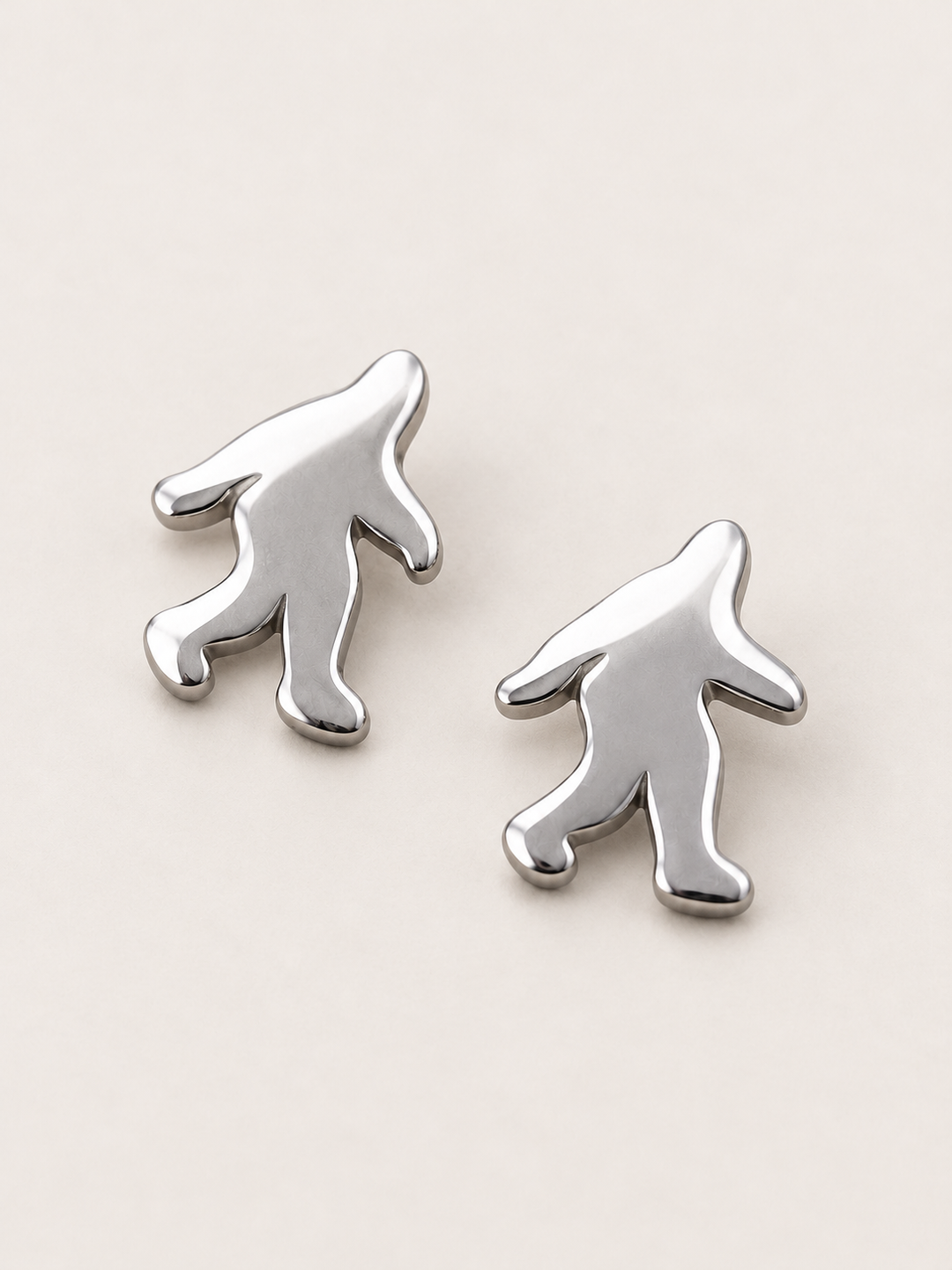 Silver Bigfoot Stud Earrings shown angled on a warm neutral background