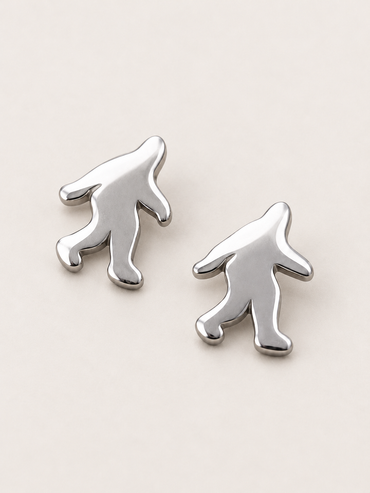 Silver Bigfoot Stud Earrings shown angled on a warm neutral background