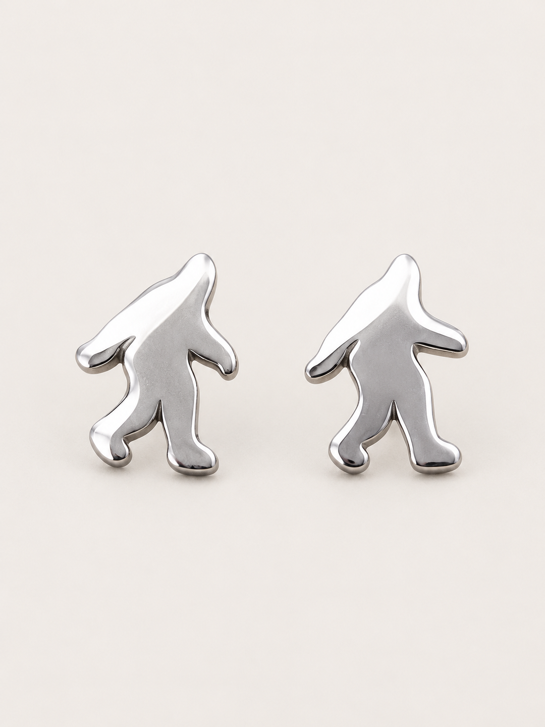 Silver Bigfoot Stud Earrings in stainless steel on a warm neutral background